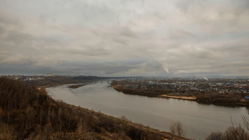 clouds hovering above a river with the city of pittsburgh in the distance