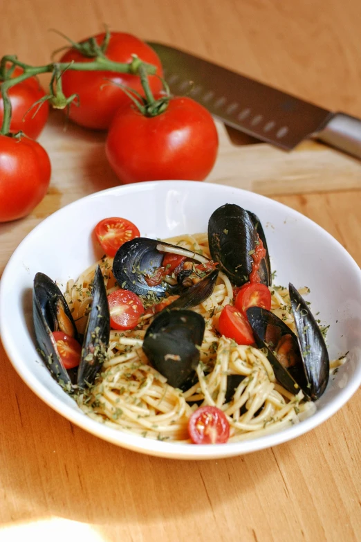 a plate of spaghetti with mussels and tomatoes