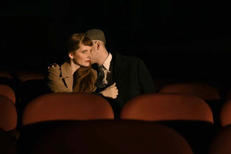 a man and woman cuddle in the theater seats