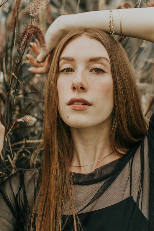 the girl has long red hair and is standing in a field