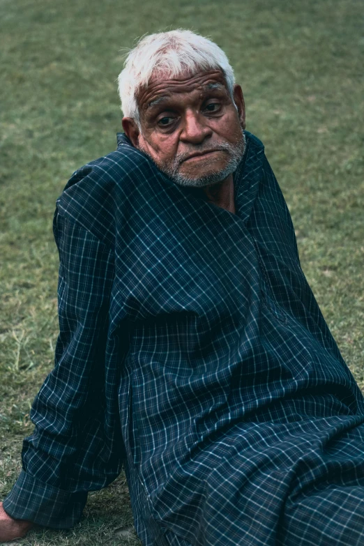 an old man with grey hair sitting on the ground