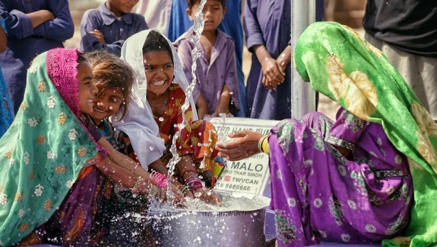 many indian women in colorful sars bathing a large bowl