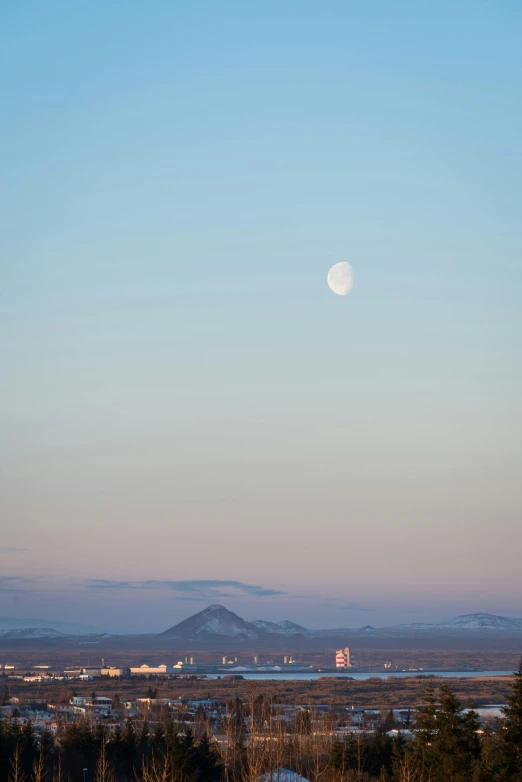 a clear sky with the moon shining on top of a mountain