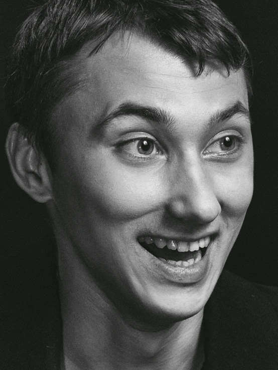 a smiling young man in a black shirt with a smile on his face