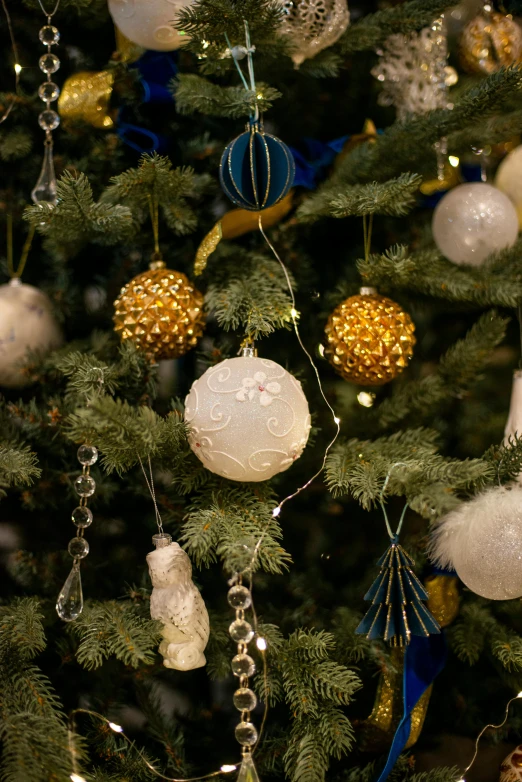 a tree with ornaments is adorned with gold and blue ribbons