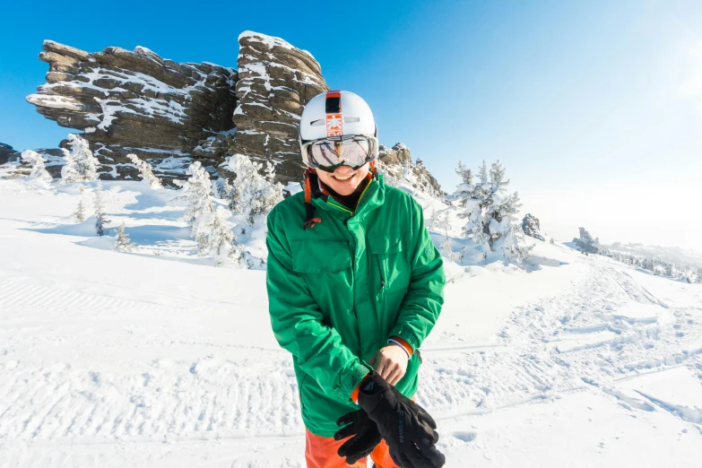 a snowboarder in an orange and green jacket posing on a slope