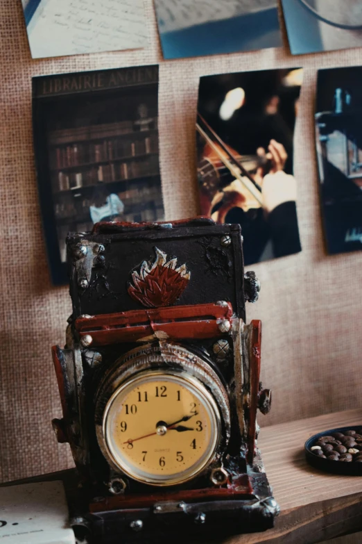 a clock sitting on a desk with pictures hanging above