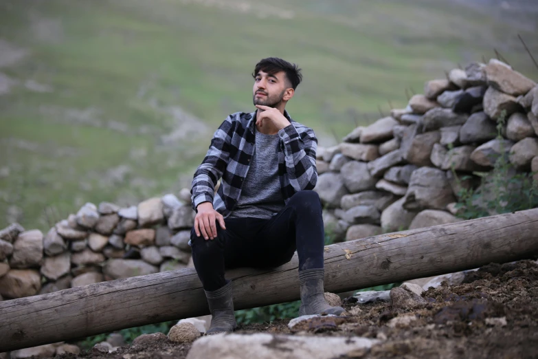 a man sitting on top of a log looking off into the distance