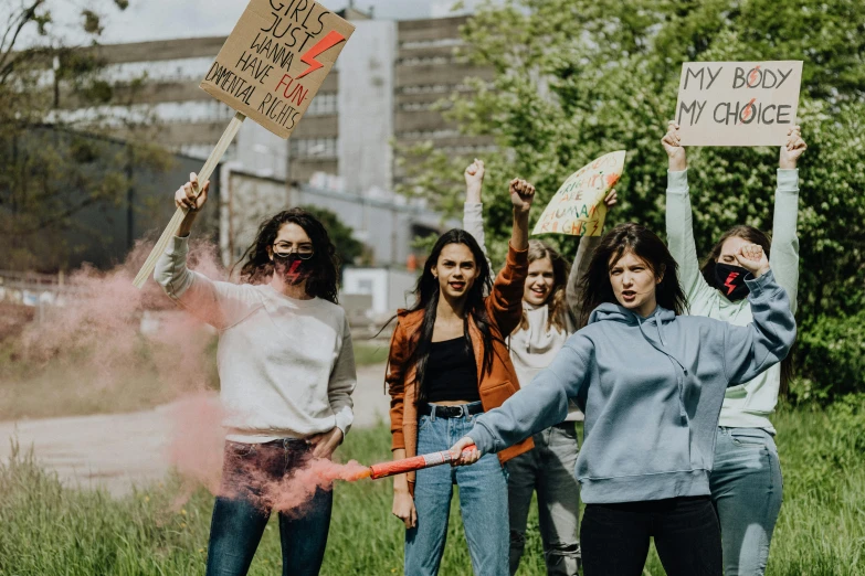 a group of friends gathered outside holding up signs