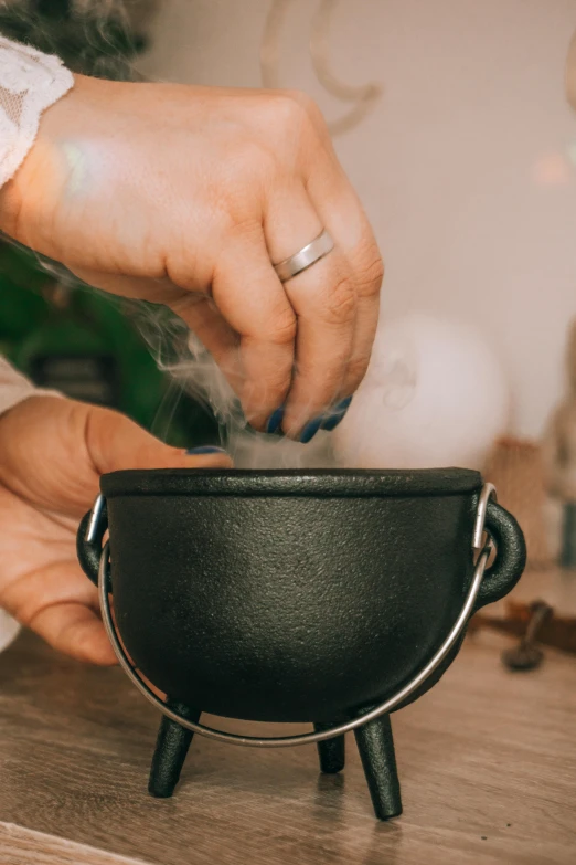 person cooking food over a frying pan with the lid down