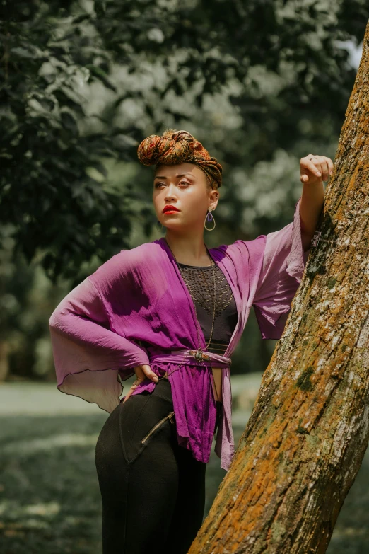 a girl leans against a tree in a park