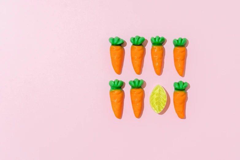 five small carrots are standing next to one orange