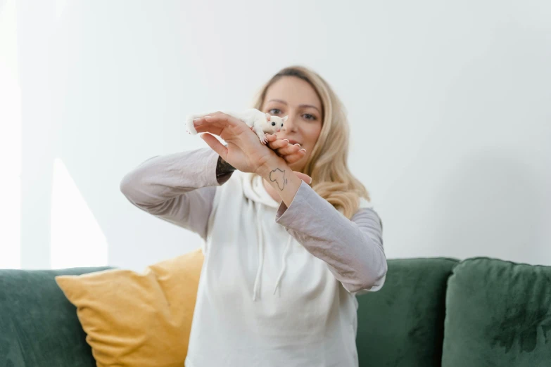 a blonde woman holding a small white object while posing for the camera