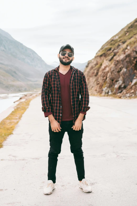 a man standing on the edge of a road wearing sun glasses