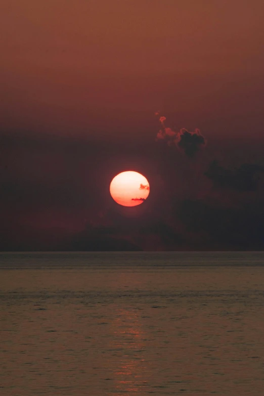 a sunrise over the ocean with a boat out side