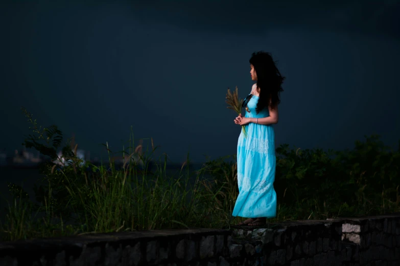 a woman in a blue dress holding flowers and posing