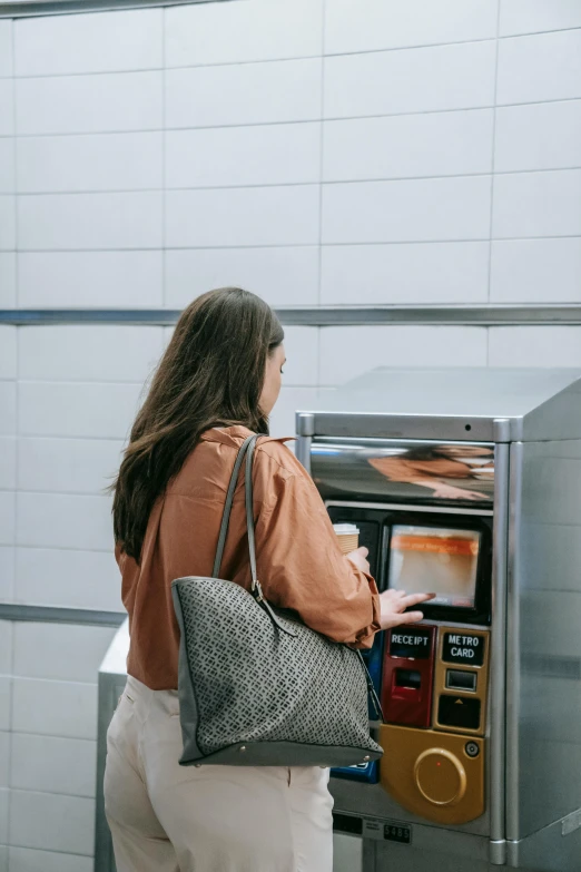 a lady looking at the trash machine in the subway