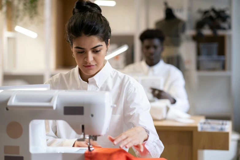 a woman using a sewing machine with another person watching