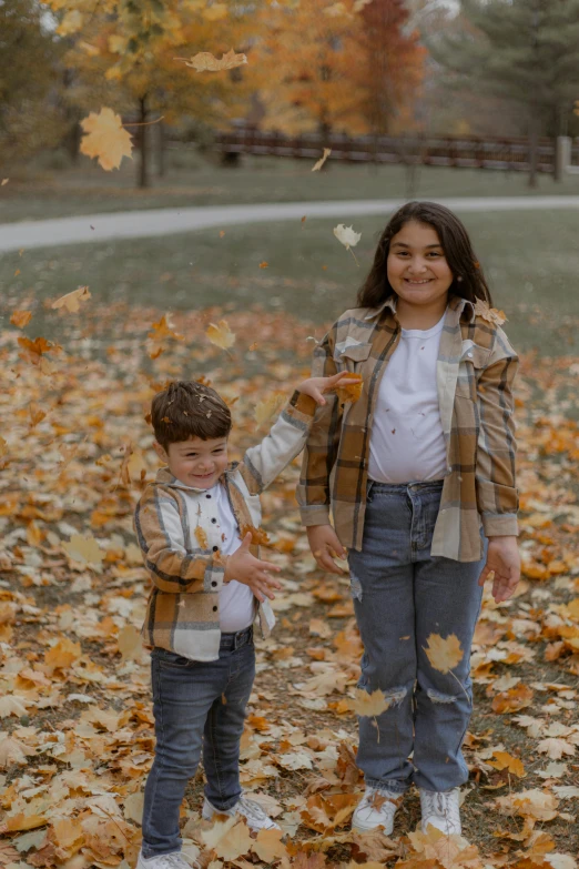 two children with fall leaves flying in the air