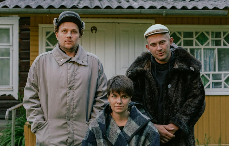 three men are posing in front of a house