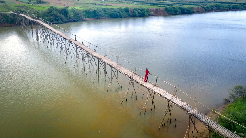 a man crosses a wooden bridge over a river