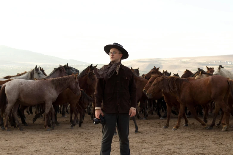 a man standing among a bunch of horses