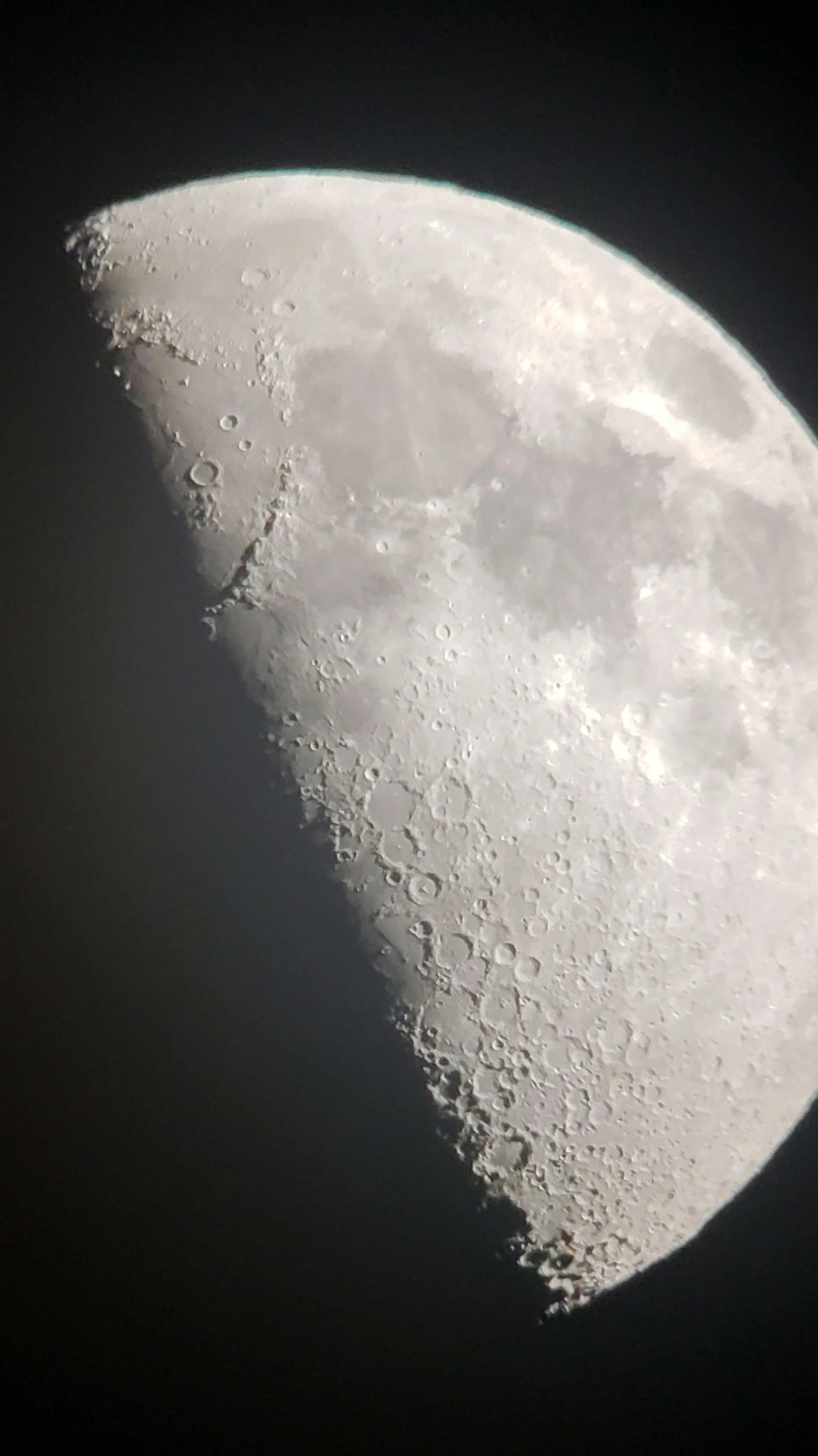 the crescent moon, with small clouds, appears to have just passed through the dark night sky