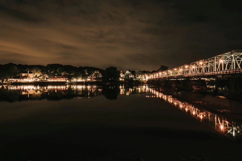 the bridge is lit up at night, reflecting in the water