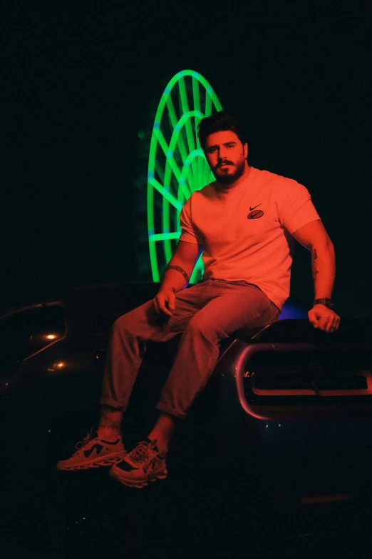 a man sits on top of a car at night