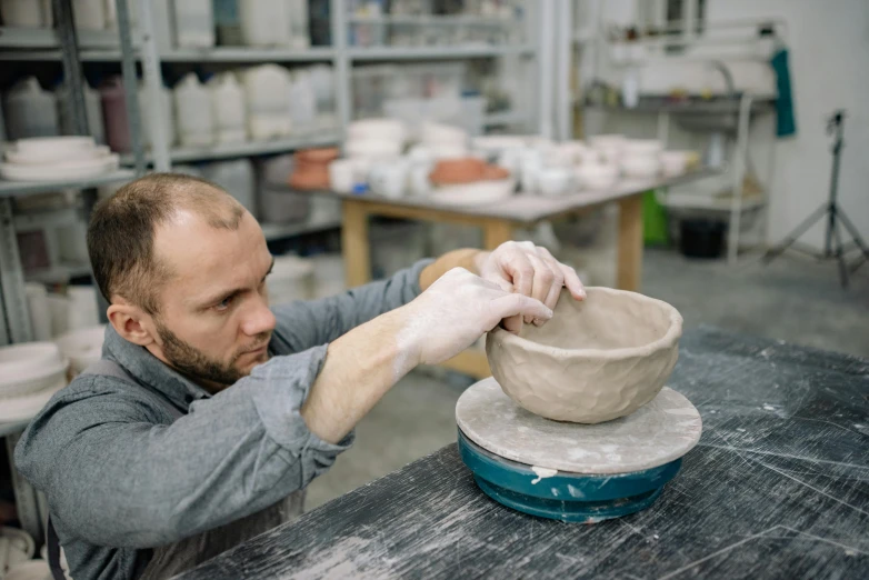 a man in an art studio working on a bowl