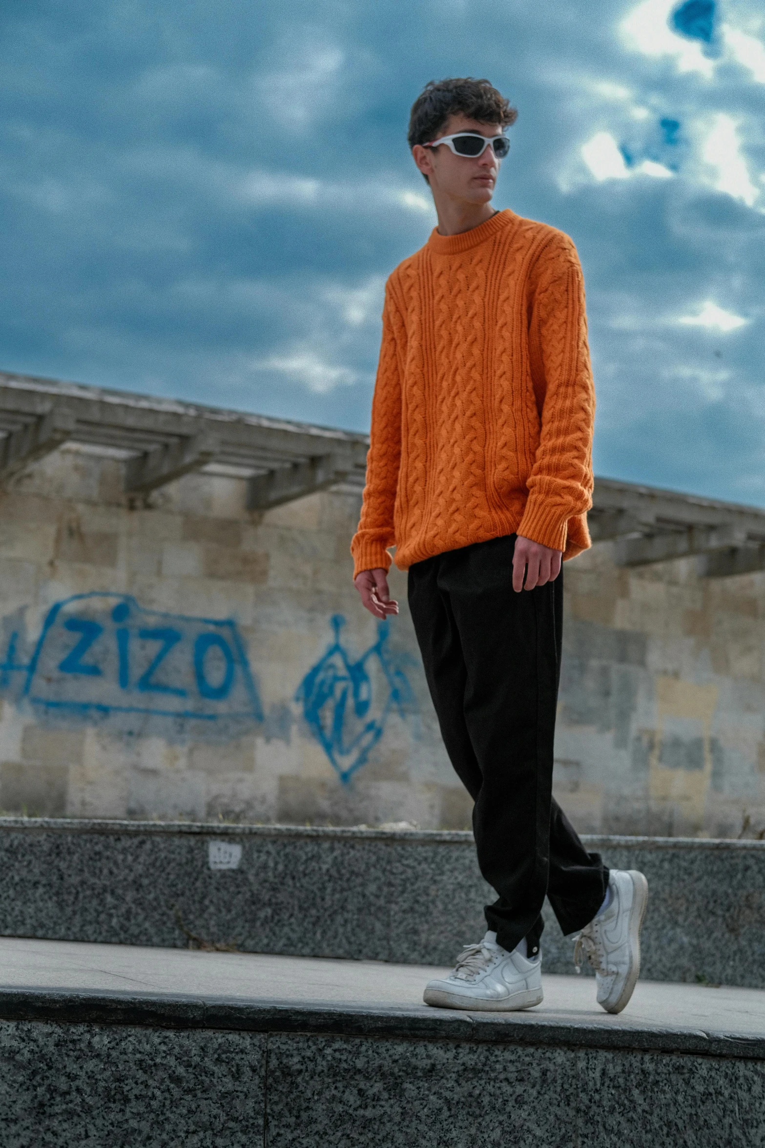 a person wearing an orange sweater standing on a ledge