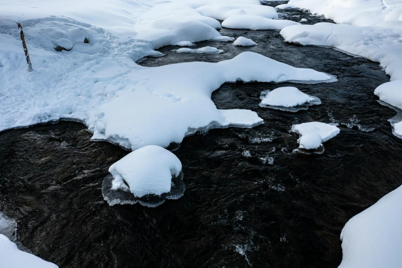 a stream running through a snow covered valley