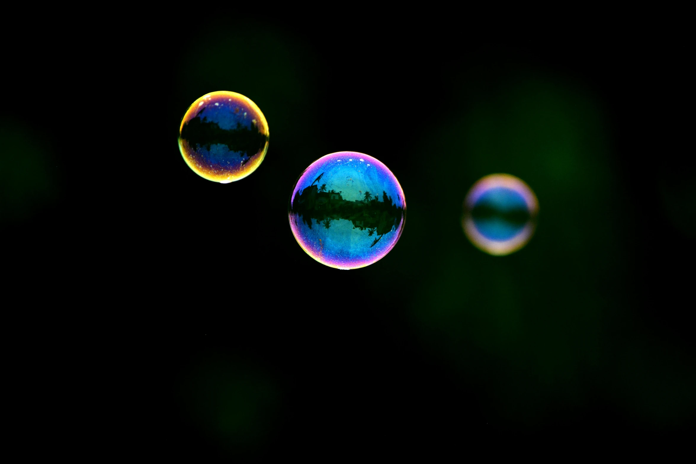 a picture of three soap bubbles being flown in the dark