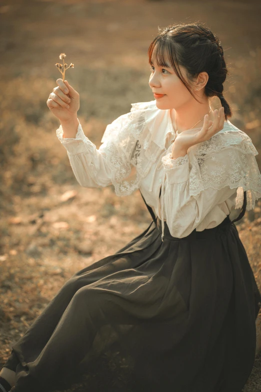 a woman in an old fashion dress holding a flower