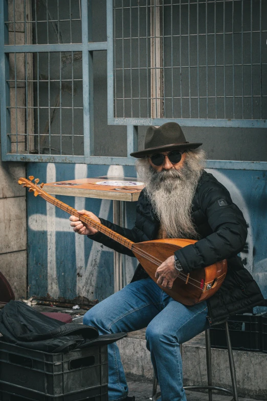 a bearded man plays a music instrument on the street