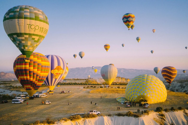 large, brightly colored balloons fly high above land