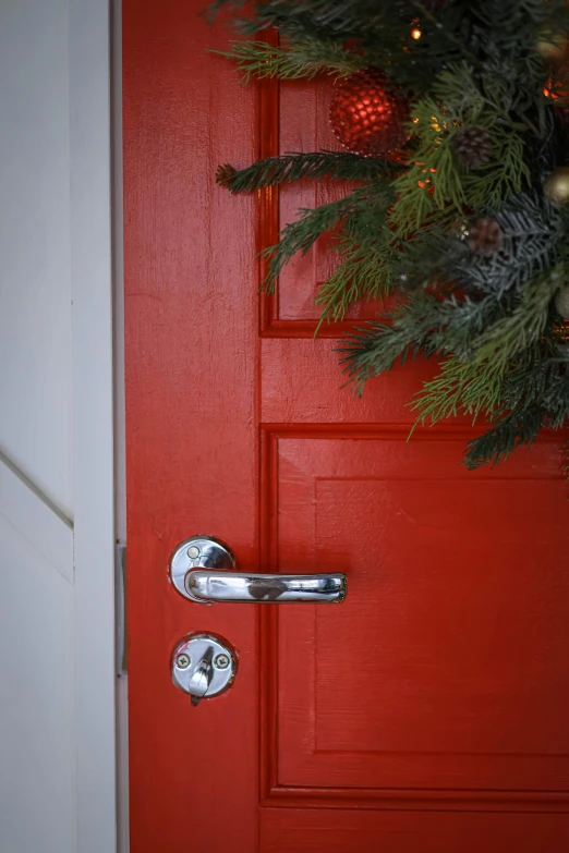 red front door with wreath and light on