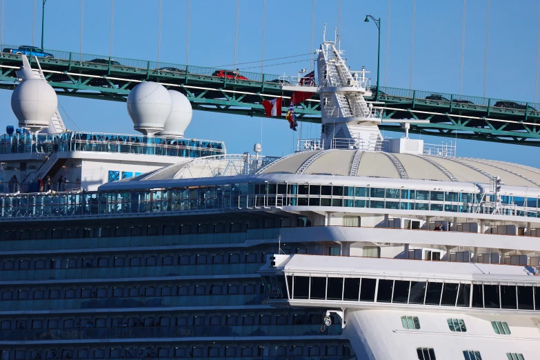 the large cruise ship is next to a bridge