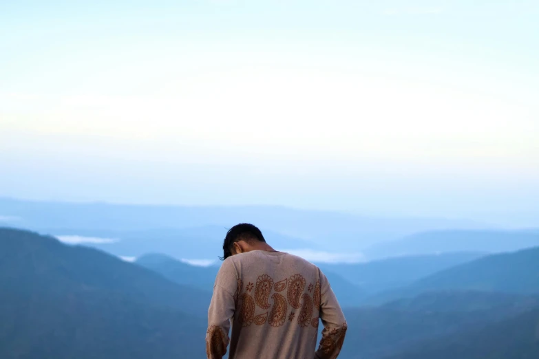 man looks down at rolling mountains in the distance