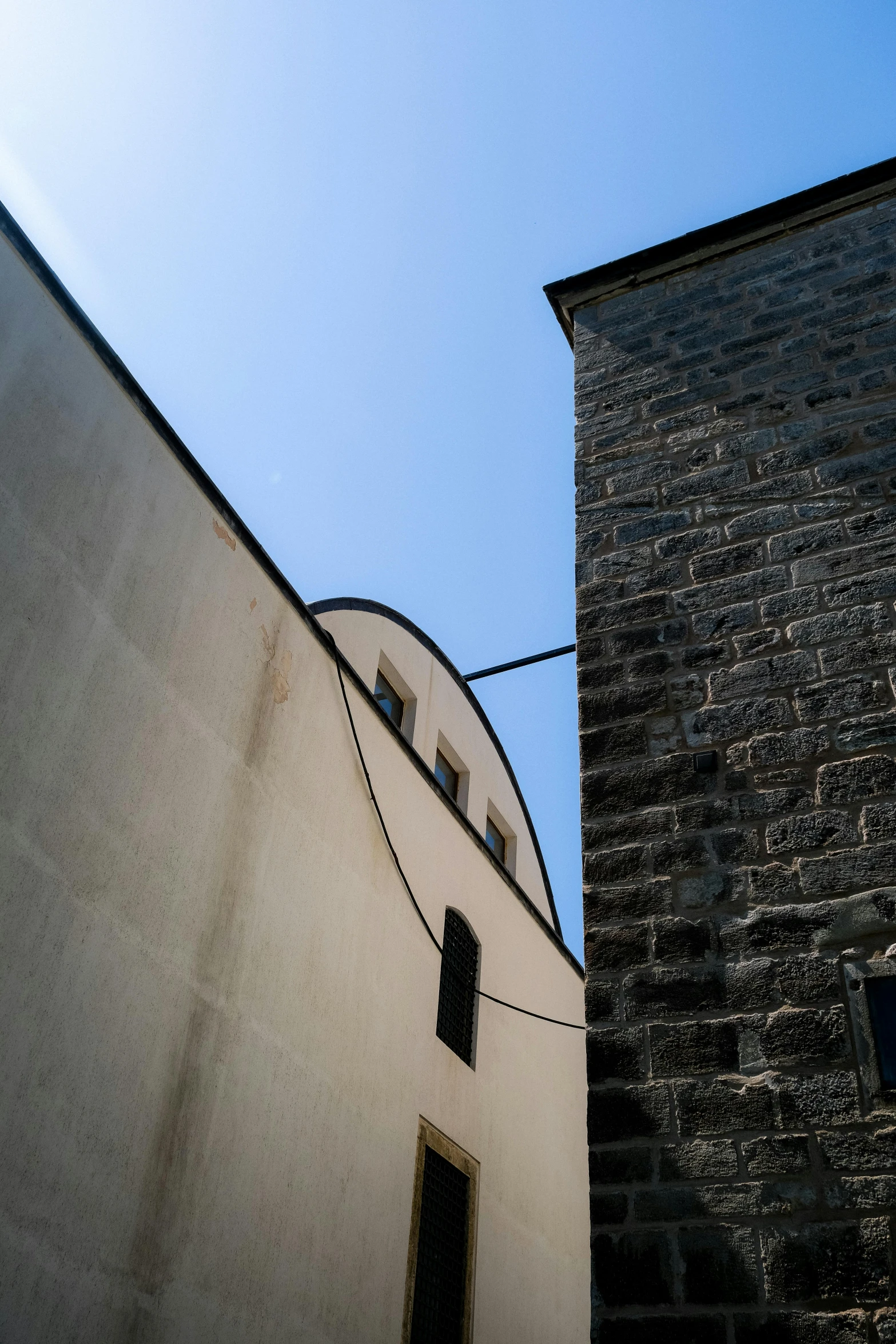 a brick building with windows on one side and a blue sky above it