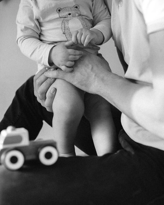 woman holding up a small child next to a wall