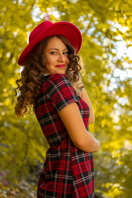 a woman with long curly hair wearing a red hat