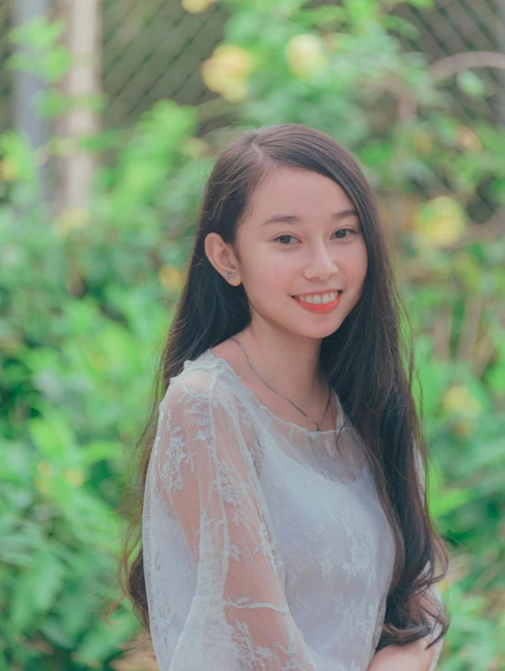 a young woman wearing a sheer top smiles for the camera