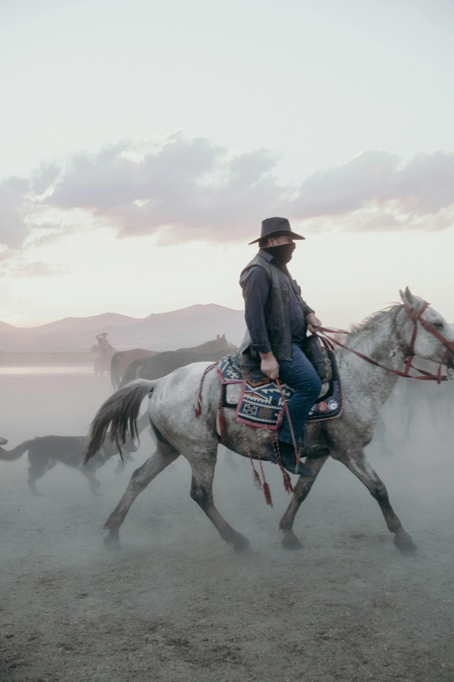 a man rides his horse and walks on the ground in front of other horses