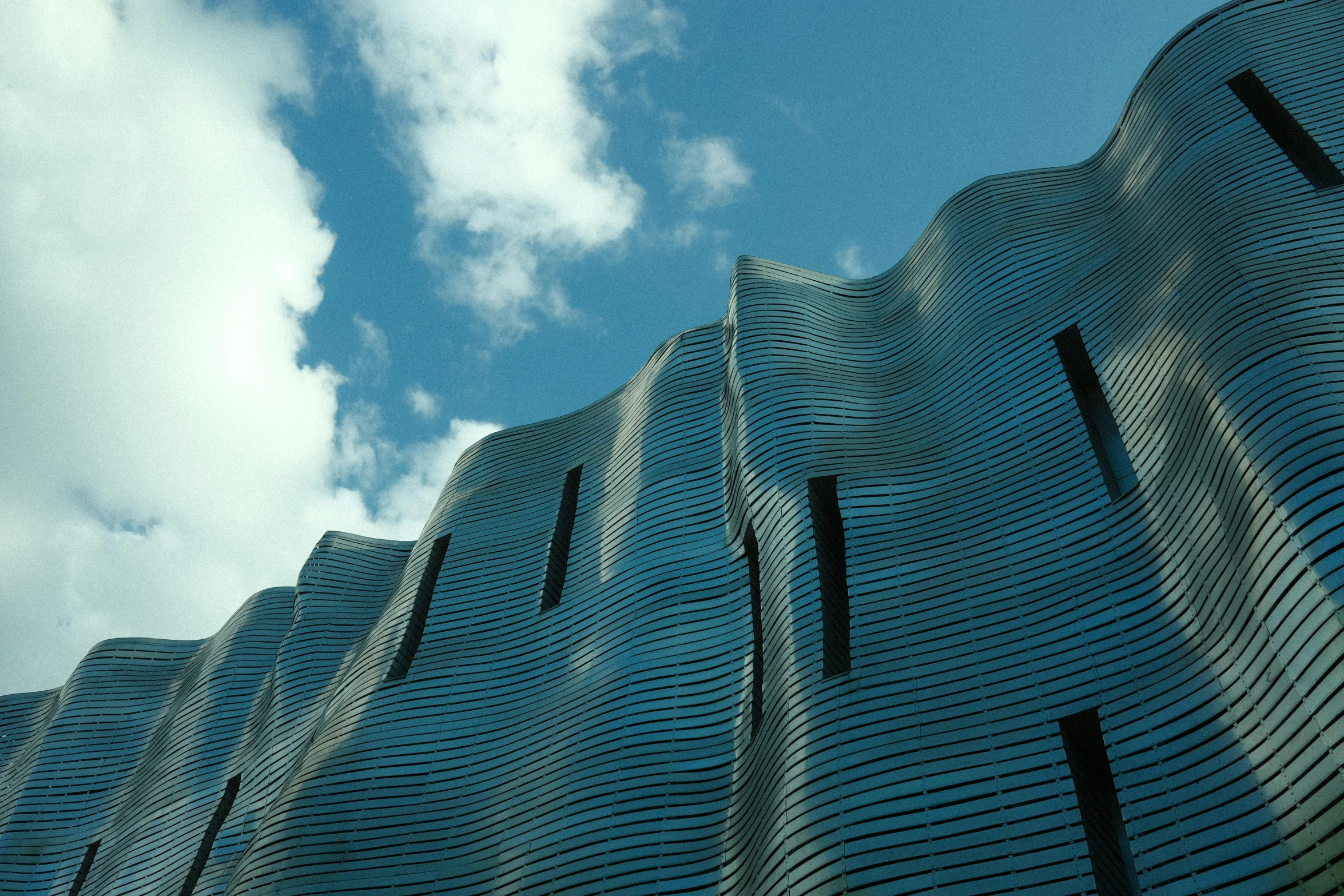 blue sky and clouds behind a wall with large metal panels