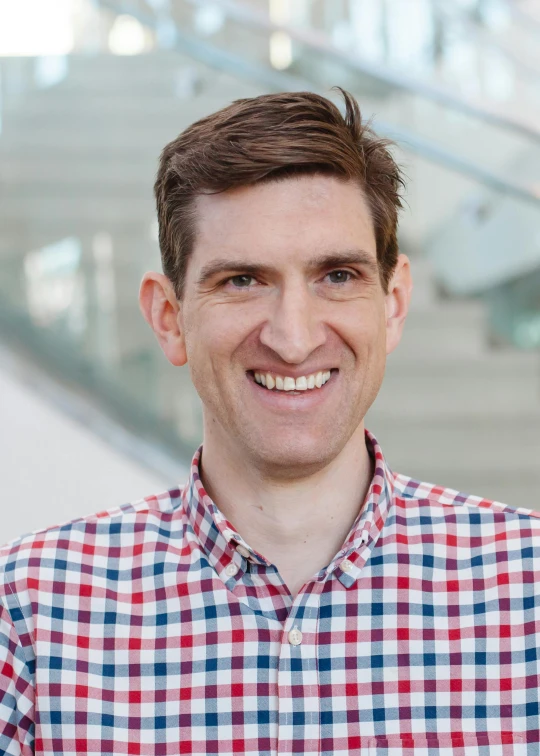 man smiling with brown hair in plaid shirt