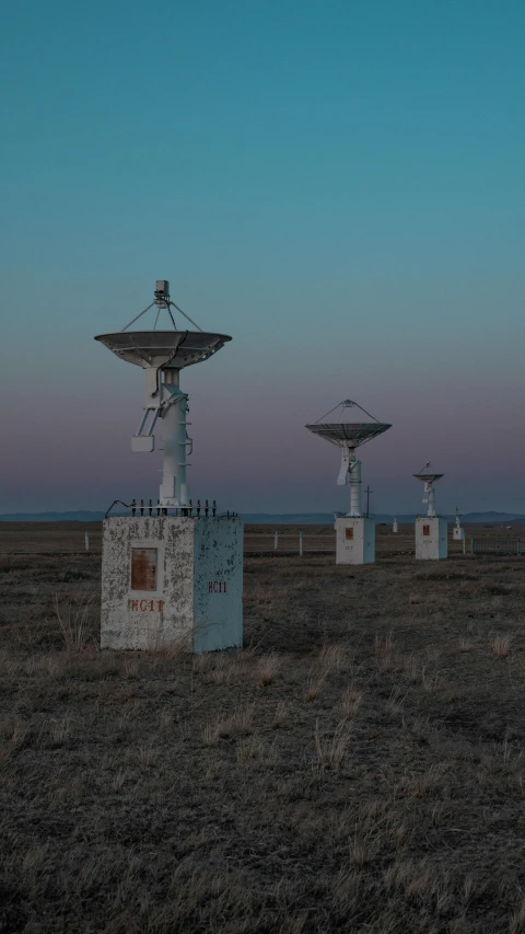 a field full of antenna dishes, some of which are sitting on top of cement blocks
