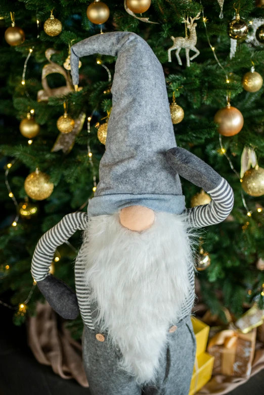 an gnome figurine that is standing near a christmas tree