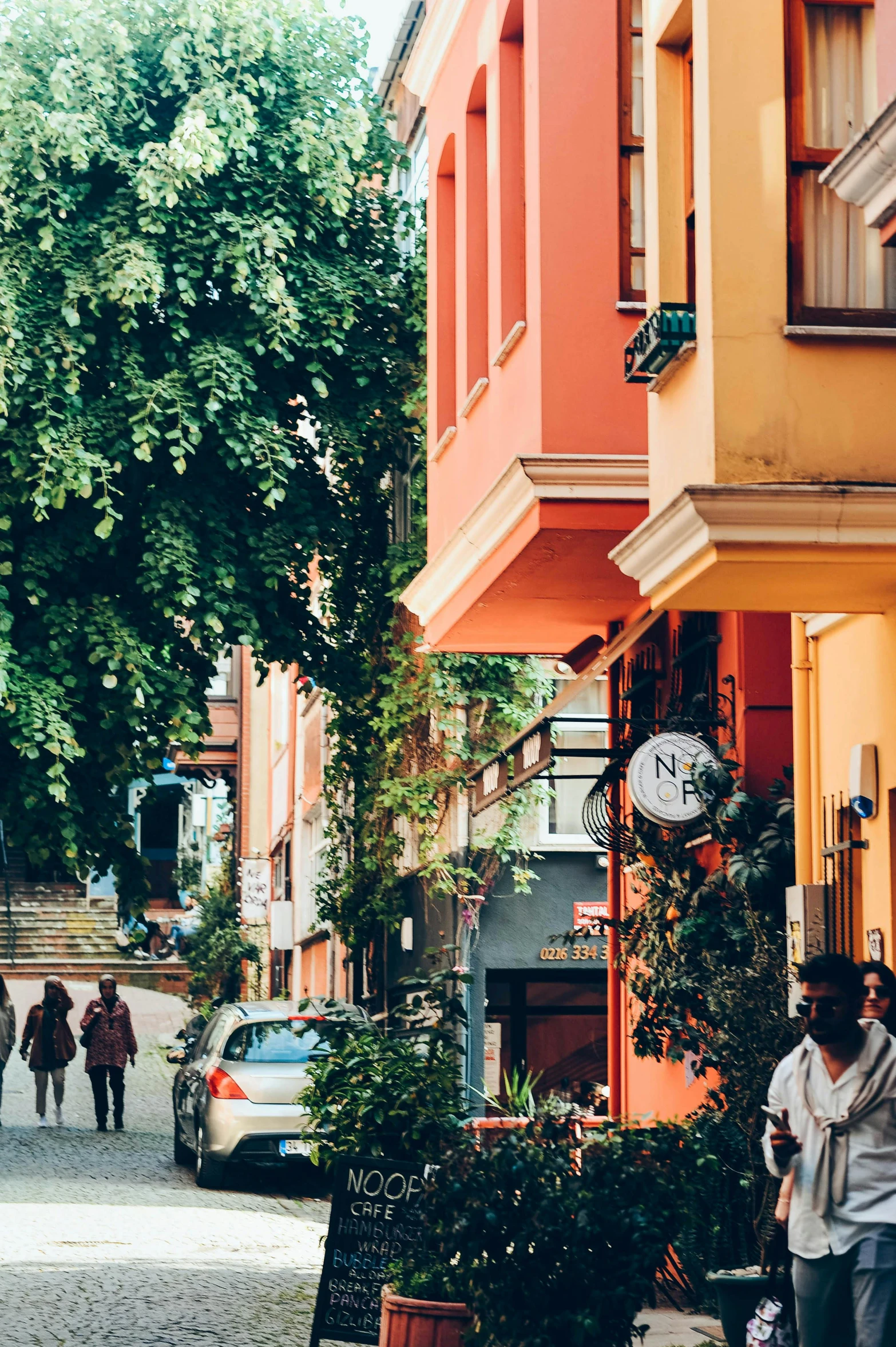 a couple walking down a street past parked cars