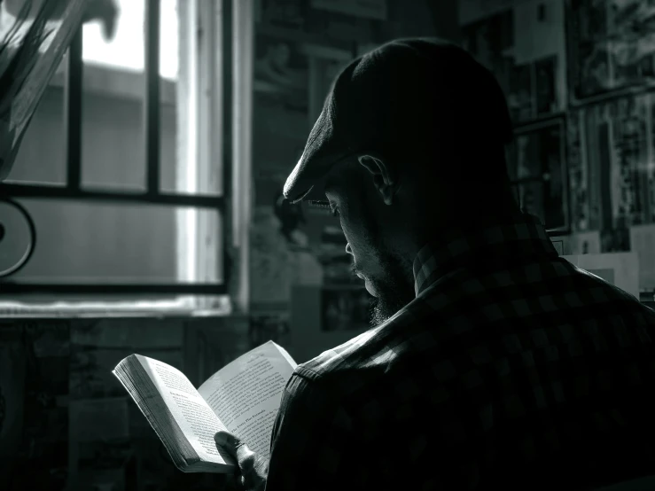 a man sitting down reading a book while reading a magazine